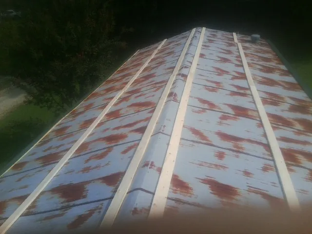 Rusted metal roof panels with new wood purlins before replacement — Storm Damage Roof Repair in Mankato by Roofing Brothers
