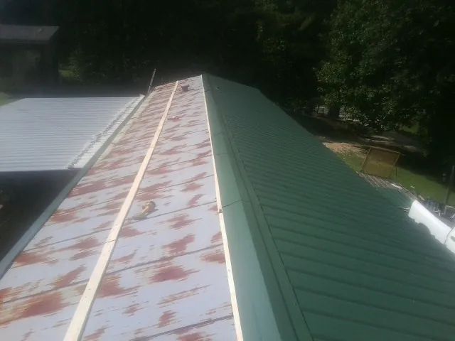 Old rusted panels beside newly installed green metal roofing — Wind Damage Roof Repair by Roofing Brothers in Mankato