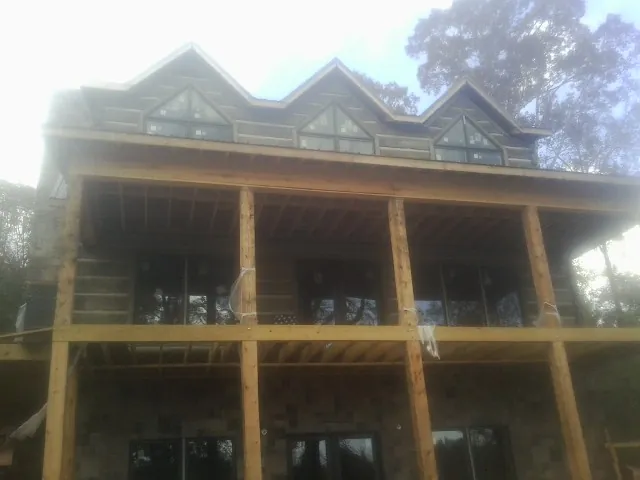 Dormers and porch framing on a large log home under construction — Roof Coating work by our crew in Mankato