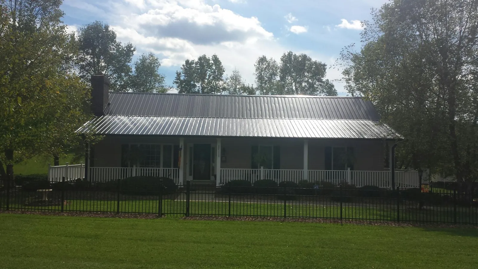Gray metal roof on a brick ranch with a full width front porch — Gutter Guard Installation work by our crew in Mankato