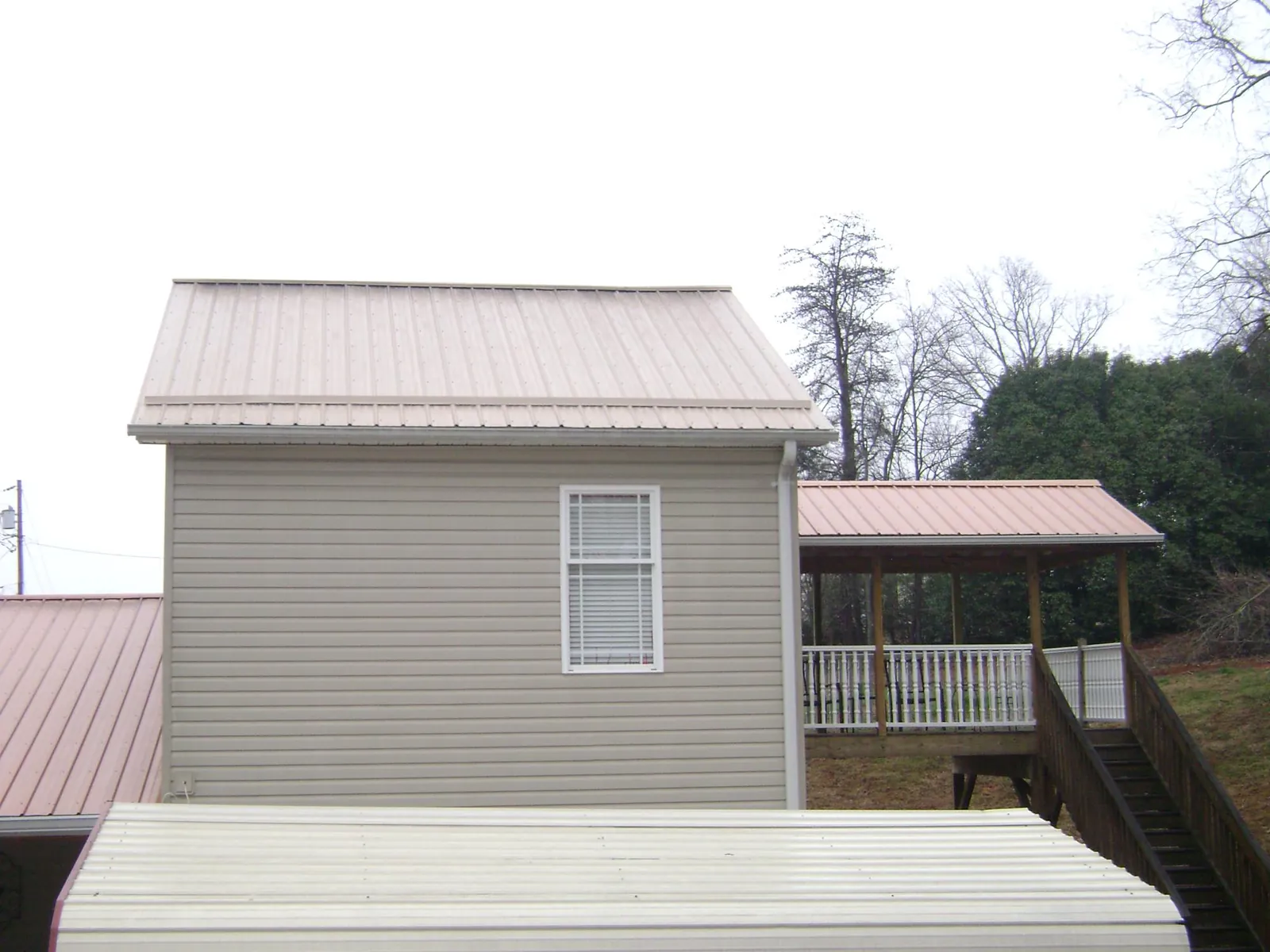 Tan metal roofs on a two story addition and attached porch, from a Roof Replacement job in Mankato