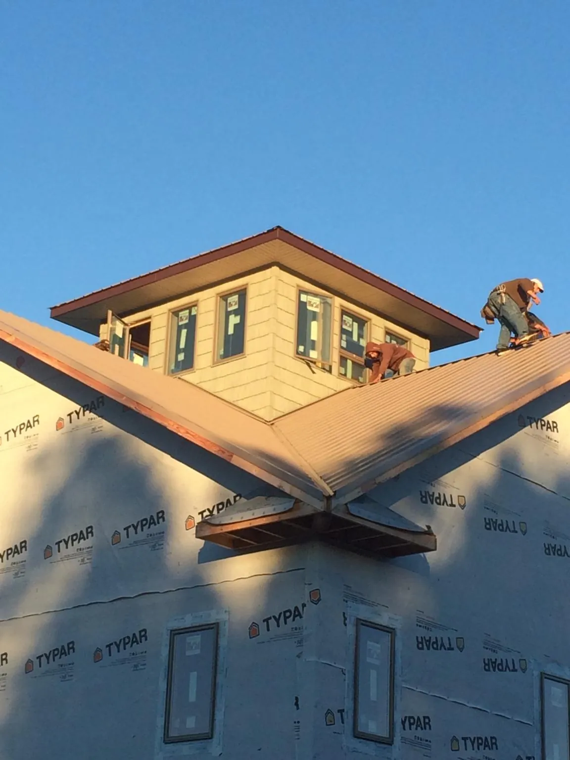 Roofers working around a rooftop cupola on a new metal roof at sunset — Roof Waterproofing in Mankato by Roofing Brothers
